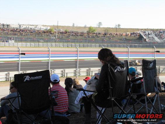 Race car on track with spectators in foreground chairs