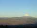 1988 Ford Bronco - A mountain peak, dusted with snow, stands tall against a blue sky, overlooking rolling hills.