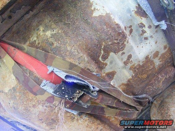 Rusted interior floor with seatbelt and camouflage fabric