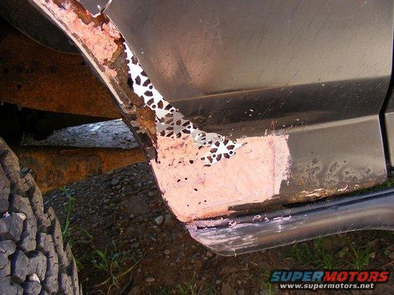 Rusted wheel well with body filler and exposed metal