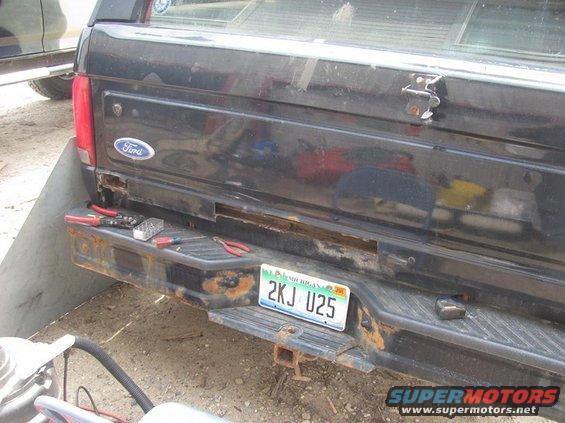 Black Ford truck tailgate with a rusty bumper and a Michigan license plate reading 2KJ U25