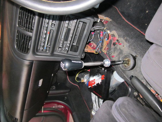 Car interior showing center console with aftermarket short shifter and wiring