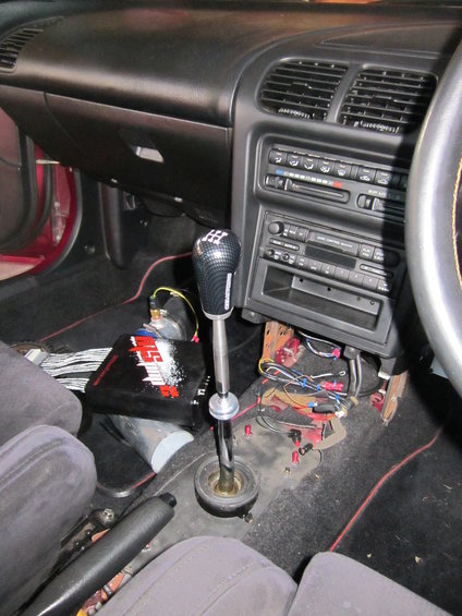 Custom short shifter with extended shaft and carbon fiber knob in a car interior