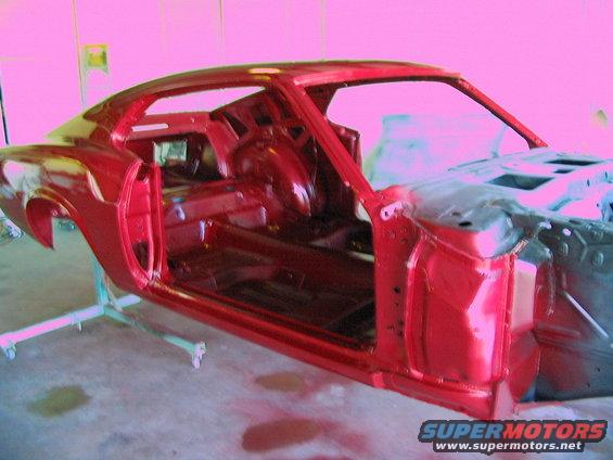 Red 1970 Ford Mustang body shell, interior stripped, on paint stands