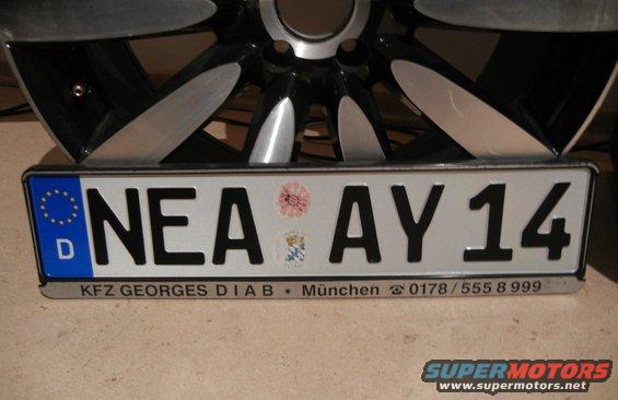 German license plate NEA AY 14 in front of a car wheel