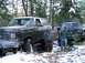 1988 Ford Bronco - Two men stand next to a very muddy Ford Bronco and another off-road vehicle in a snowy, wooded environment.