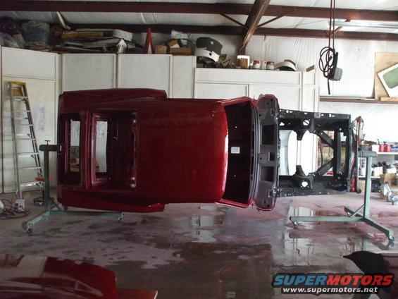 Red 1970 Ford Mustang body on rotisserie, upside down