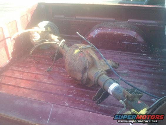 Rear axle assembly with brake drum and suspension components, lying in the bed of a pickup truck