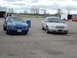 2003 Ford Crown Victoria - A silver Ford Crown Victoria and a blue Ford Mustang drag car are parked side-by-side at a drag strip.