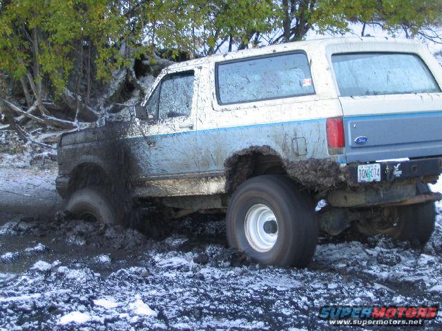 1988 Ford Bronco stuck in mud and snow, rear 3/4 view