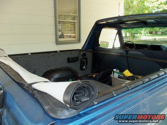 Interior of blue SUV with rolled soft top in bed. Supermotors.net logo visible