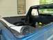 1985 Ford Bronco - The interior of a blue SUV shows a rolled-up soft top in the cargo area, with the Supermotors.net logo visible on the lower right.