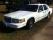 1997 Lincoln Town Car - A white sedan is parked outdoors next to a dark pickup truck.