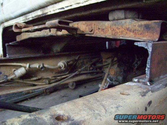 Undercarriage view of rusty truck frame with visible fuel lines and suspension components