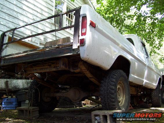 White 1972 Ford F-150 pickup truck, rear view, flatbed installed, on blocks