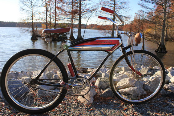 Red and chrome bicycle with red handlebars and seat, parked by a lake