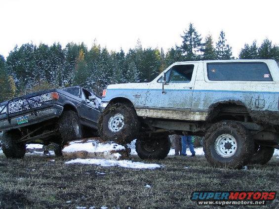 1988 Ford Bronco and another truck off-roading over a log