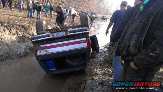 1996 Ford Bronco overturned in mud with people watching