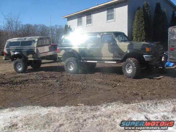 Camouflaged Ford Bronco towing a camouflaged trailer, side view