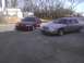 2003 Ford Crown Victoria - Two sedans, a silver Ford Crown Victoria and a maroon Mercury Grand Marquis, are parked outside.