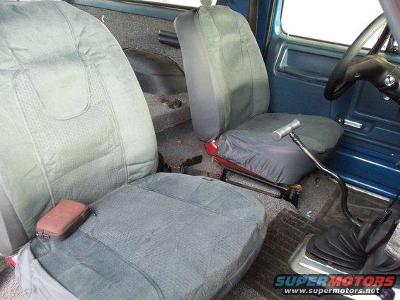 Interior view of a vehicle with two front seats, a floor shifter, and a steering wheel. The seats are covered