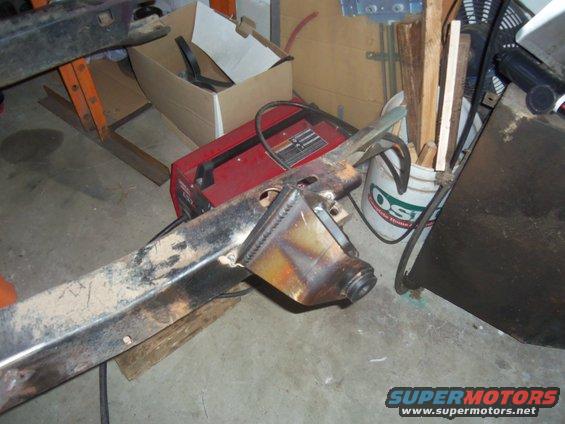 Welding project on a metal frame with a red welder and bucket of wood in background