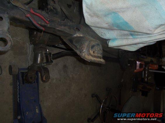 vehicle frame supported by jacks, with suspension parts visible