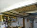 2004 Aston Martin Virage - A cluttered garage interior shows storage shelves filled with items, along with exposed ceiling joists and insulation panels.