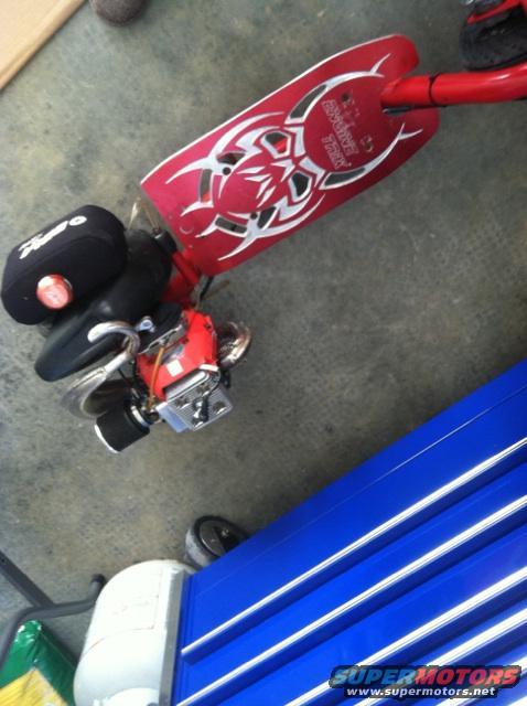 Red gas scooter with tribal graphics and a small engine. Next to a blue toolbox