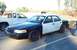 2001 Ford Crown Victoria - A two-tone sedan is parked next to a white pickup truck on a sunny day.