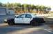 2001 Ford Crown Victoria - A black and white police car is parked outside a building with trees in the background.