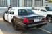 2001 Ford Crown Victoria - A black and white 2001 Ford Crown Victoria police car is parked next to a white pickup truck.