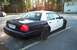 2001 Ford Crown Victoria - A two-tone police car is parked in a lot, with a second police car visible in the distance.