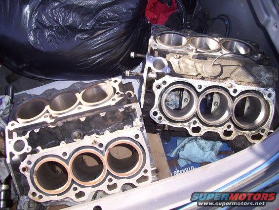two engine blocks, one with three cylinders visible, the other with three cylinders visible, in a vehicle's trunk