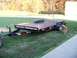 1995 Mercury Grand Marquis - A dog investigates a black car hauler trailer parked on a grassy area.
