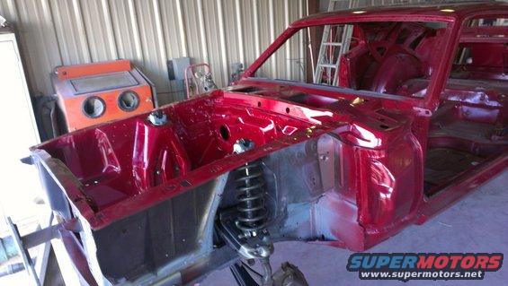 Red 1970 Ford Mustang body undergoing restoration, showing engine bay and interior structure