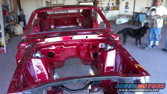 Red 1970 Ford Mustang chassis, front view, in a workshop