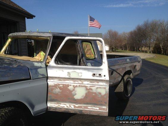 Truck body in primer with driver's door open, American flag flying