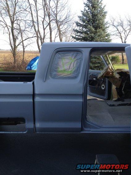 Gray 1979 Ford F-350 pickup truck, side view, primer finish, driver's door open, interior covered