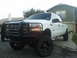 2004 Ford F-350 - This white 2004 Ford F-350 pickup truck is shown from the front three-quarter view, a prominent black grille guard and custom wheels.