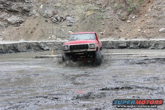 Red 1979 Ford F-Series pickup truck splashing through mud