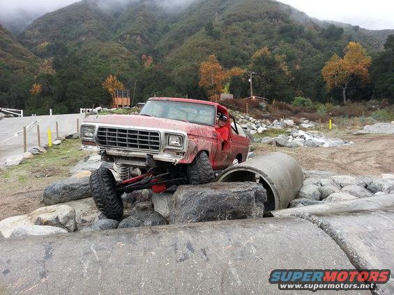 red off-road truck on rocks, driver visible