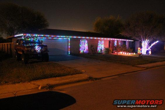 Red SUV with Christmas lights on roof and grille parked in driveway