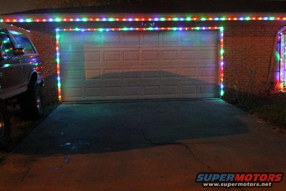 1990 Ford Bronco parked in front of a garage decorated with Christmas lights