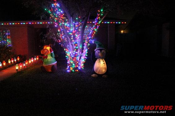 House decorated with Christmas lights, inflatable reindeer, and penguin figures