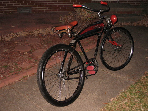 Black and red vintage bicycle with a brown seat and red handlebars