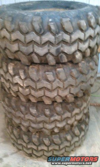 Stack of four chunky off-road tires with aggressive tread patterns