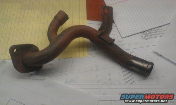 rusted metal pipe with two outlets and a flange, lying on top of some papers