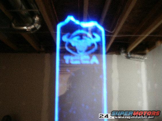 Illuminated sign with bull logo and text 'TECA' in blue light, hanging from ceiling joists