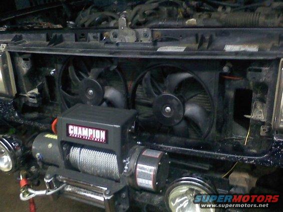 Front of vehicle showing dual electric fans, a Champion brand winch mounted below, and two round fog lights